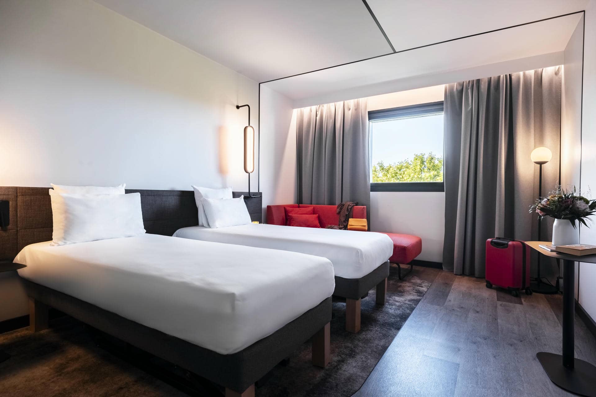 une chambre d'hôtel avec deux lits et un canapé rouge