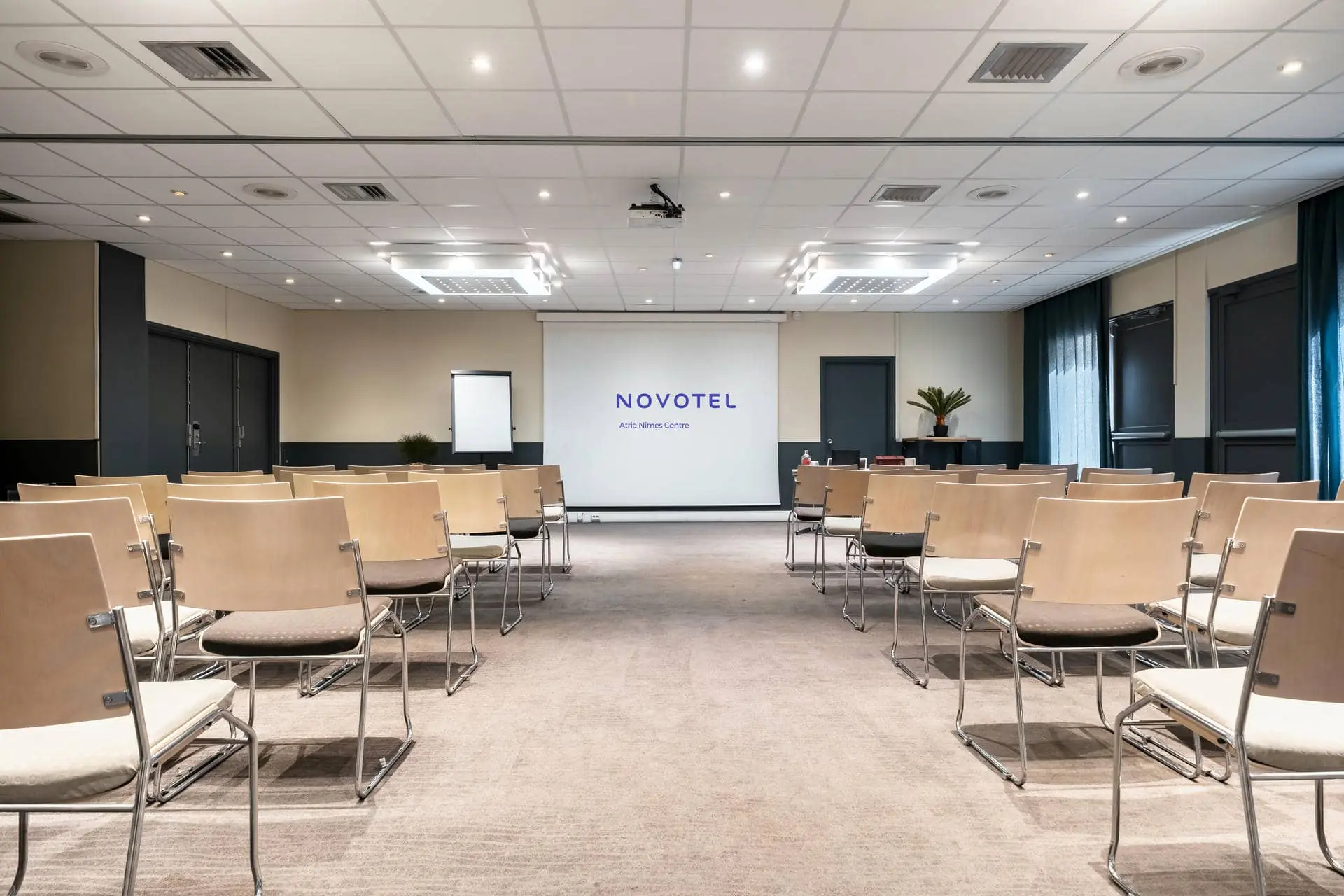 des rangées de chaises en bois devant un écran de projection sur lequel est inscrit novotel