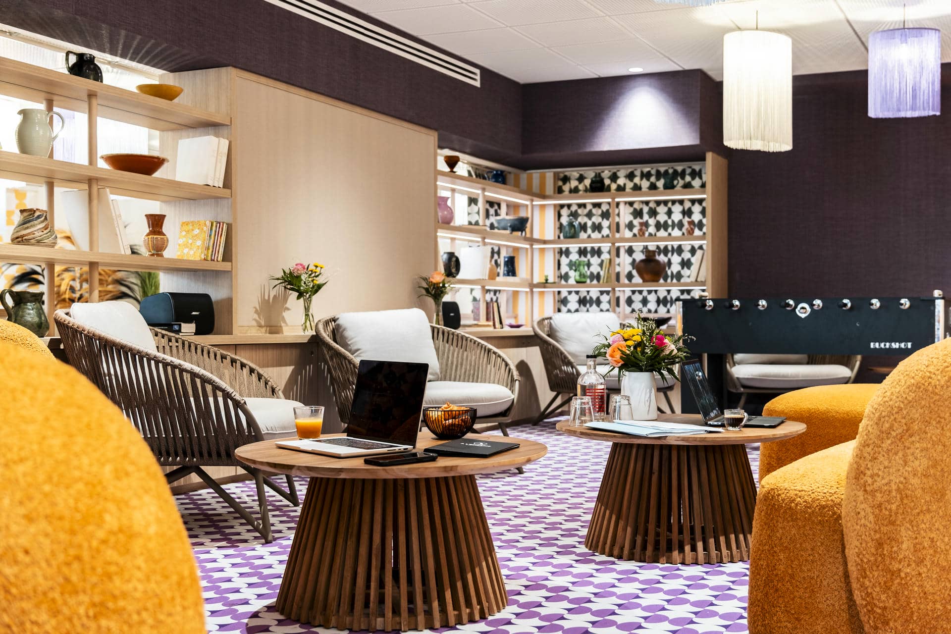 une salle avec des tables et des chaises et un baby-foot