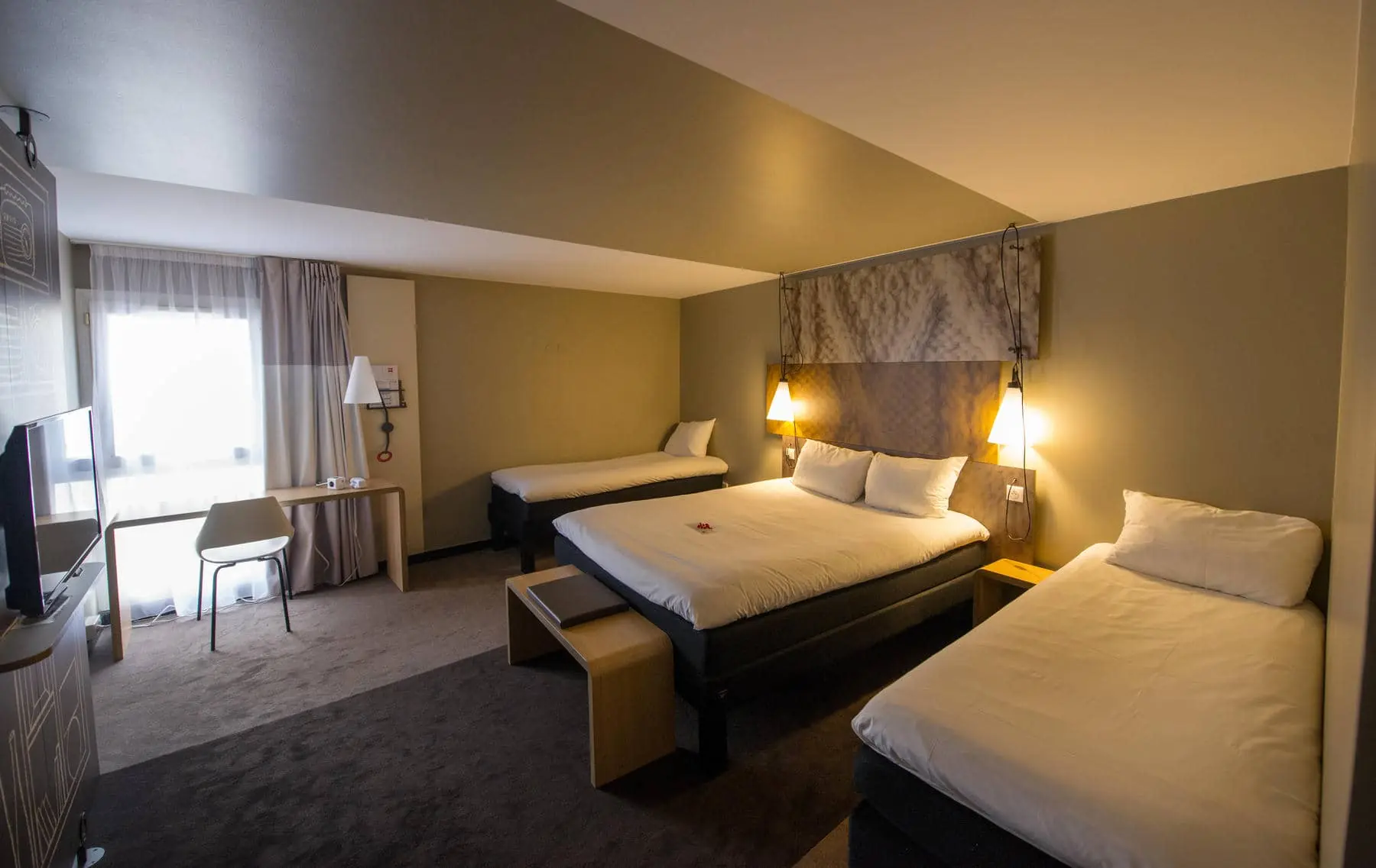 a hotel room with three beds and a desk