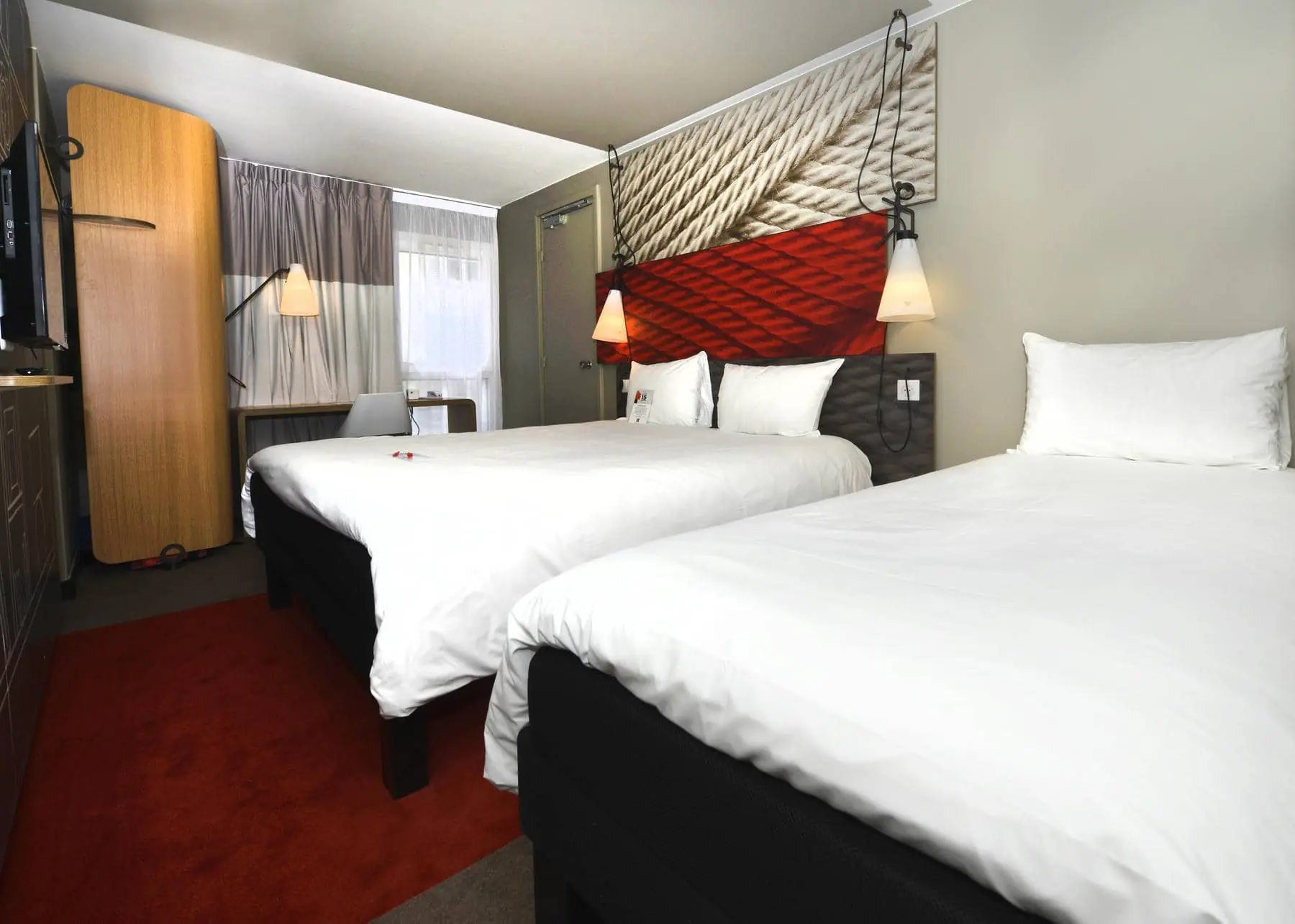 a hotel room with two beds and a lamp on the wall