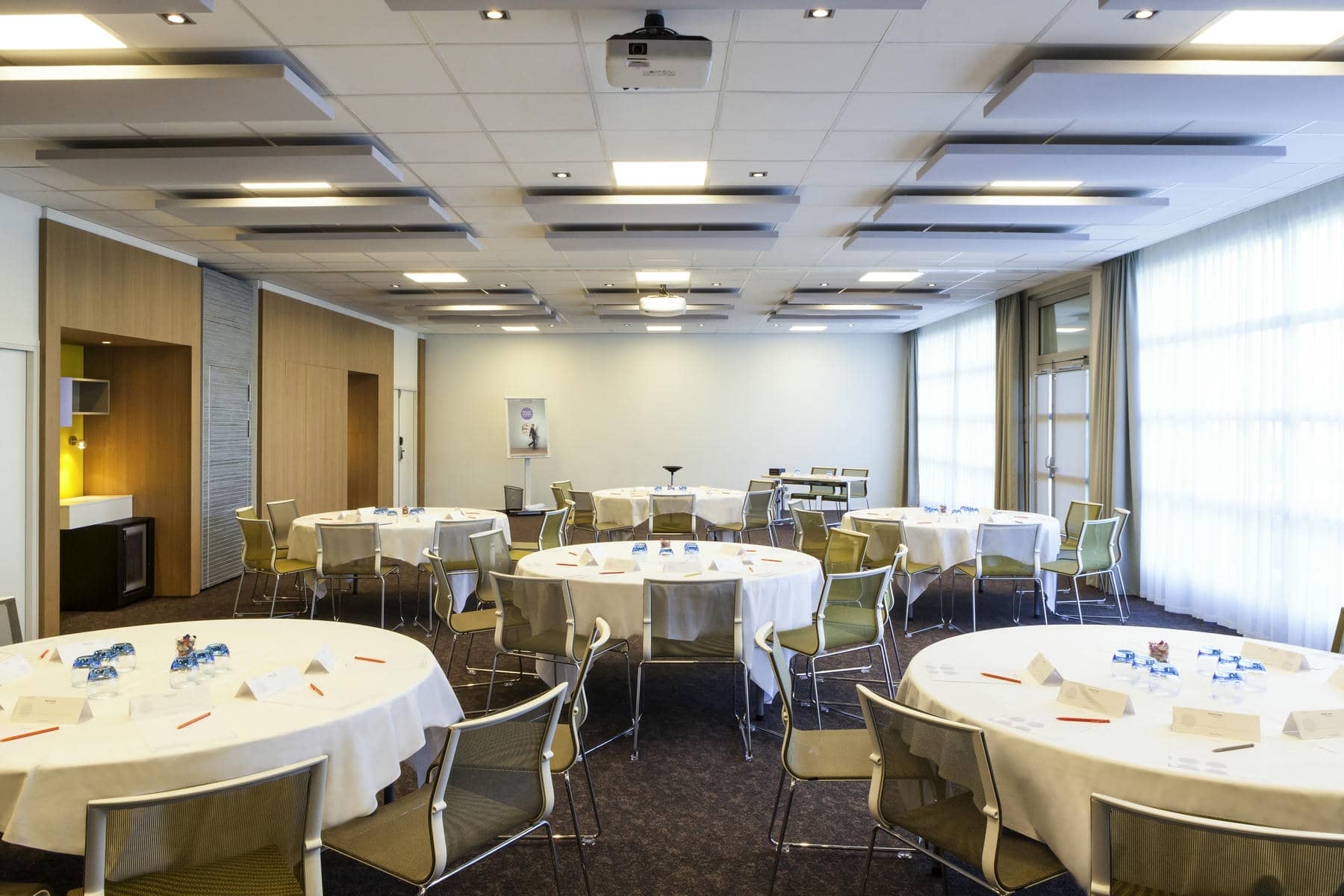 a room with tables and chairs and a projector on the ceiling