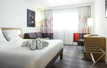 a pair of slippers with the letter x on them sit on a hotel bed