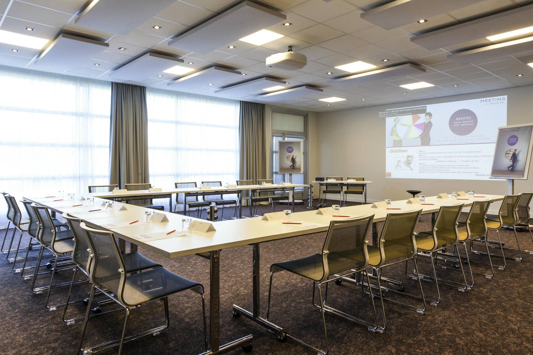 a meeting room with tables and chairs and a projector screen that says meeting