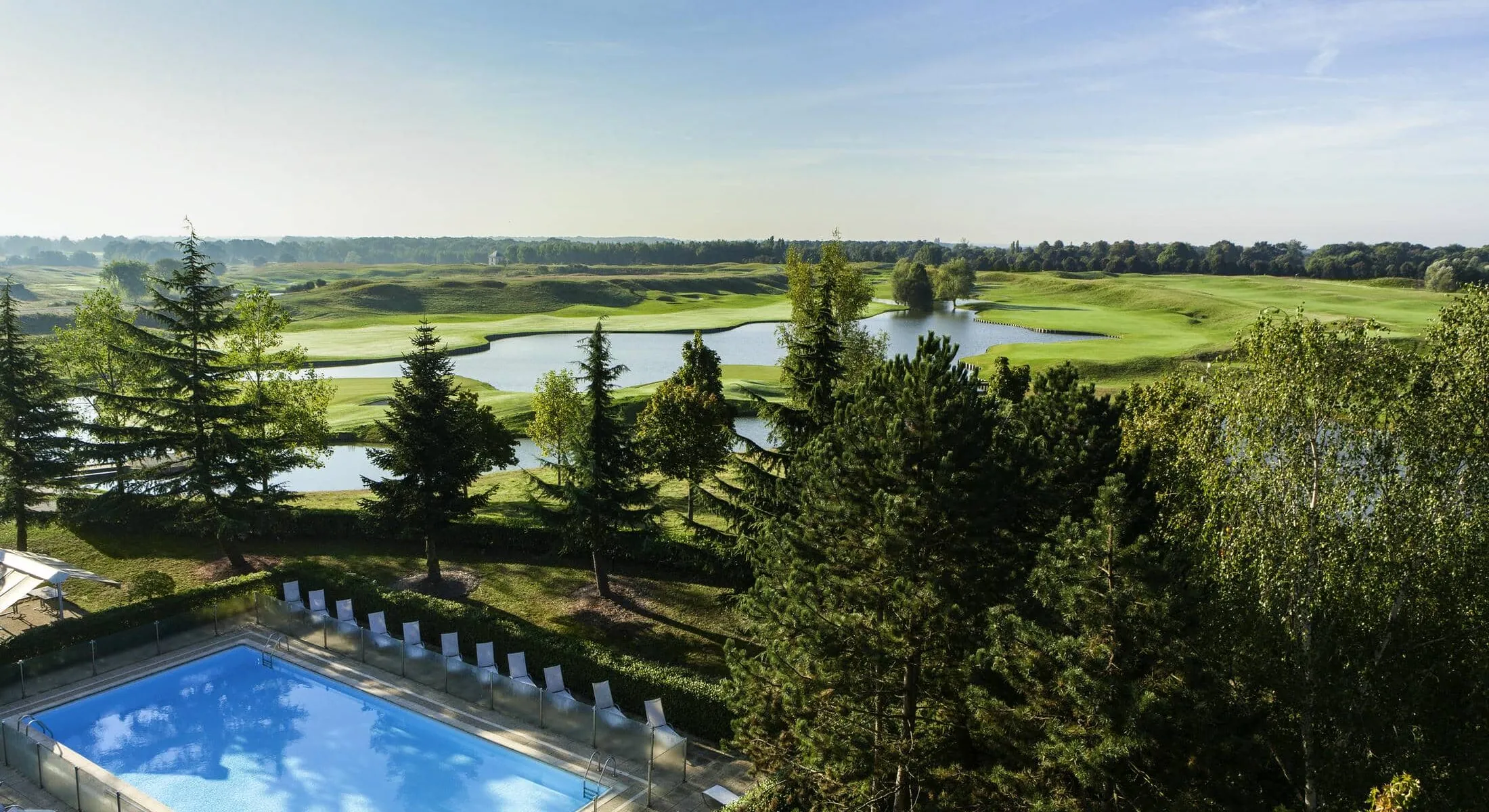 an aerial view of a swimming pool with a golf course in the background
