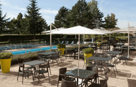 a patio with tables and chairs and umbrellas in front of a pool
