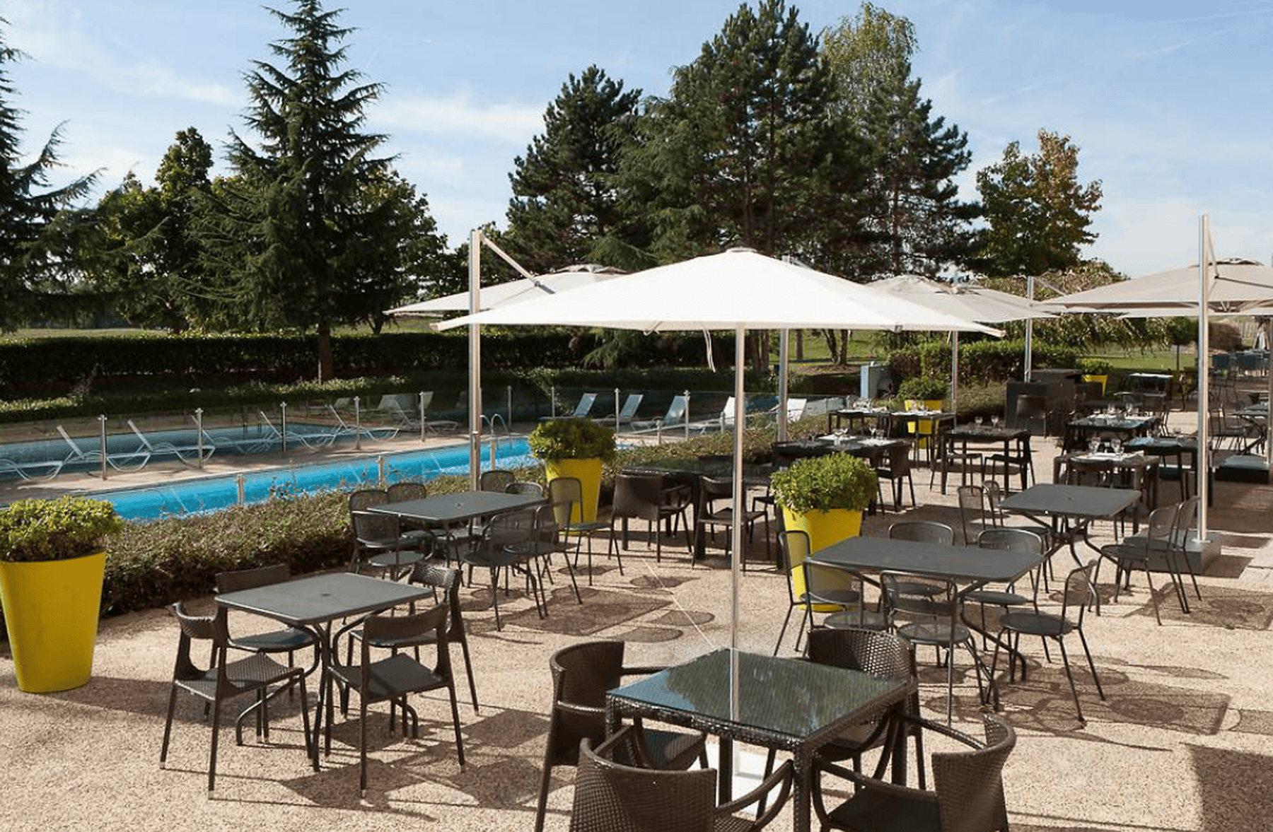 a patio with tables and chairs and umbrellas in front of a pool