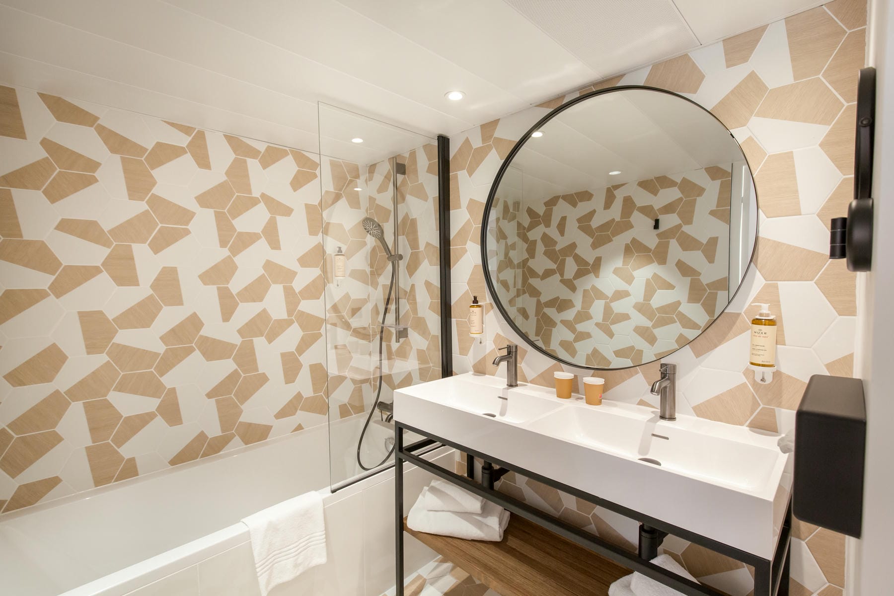 une salle de bains avec deux lavabos et un miroir rond