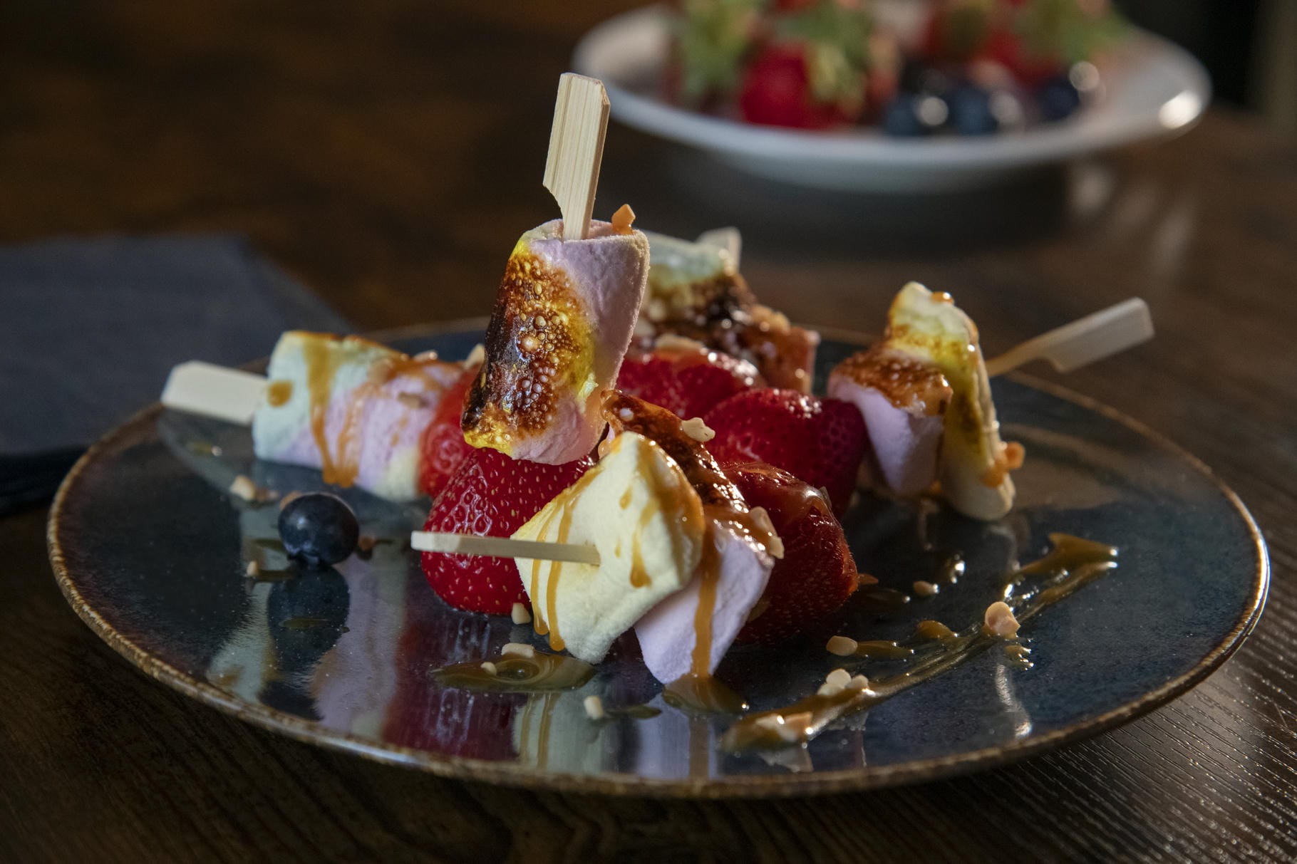 a plate of food with strawberries and marshmallows on sticks