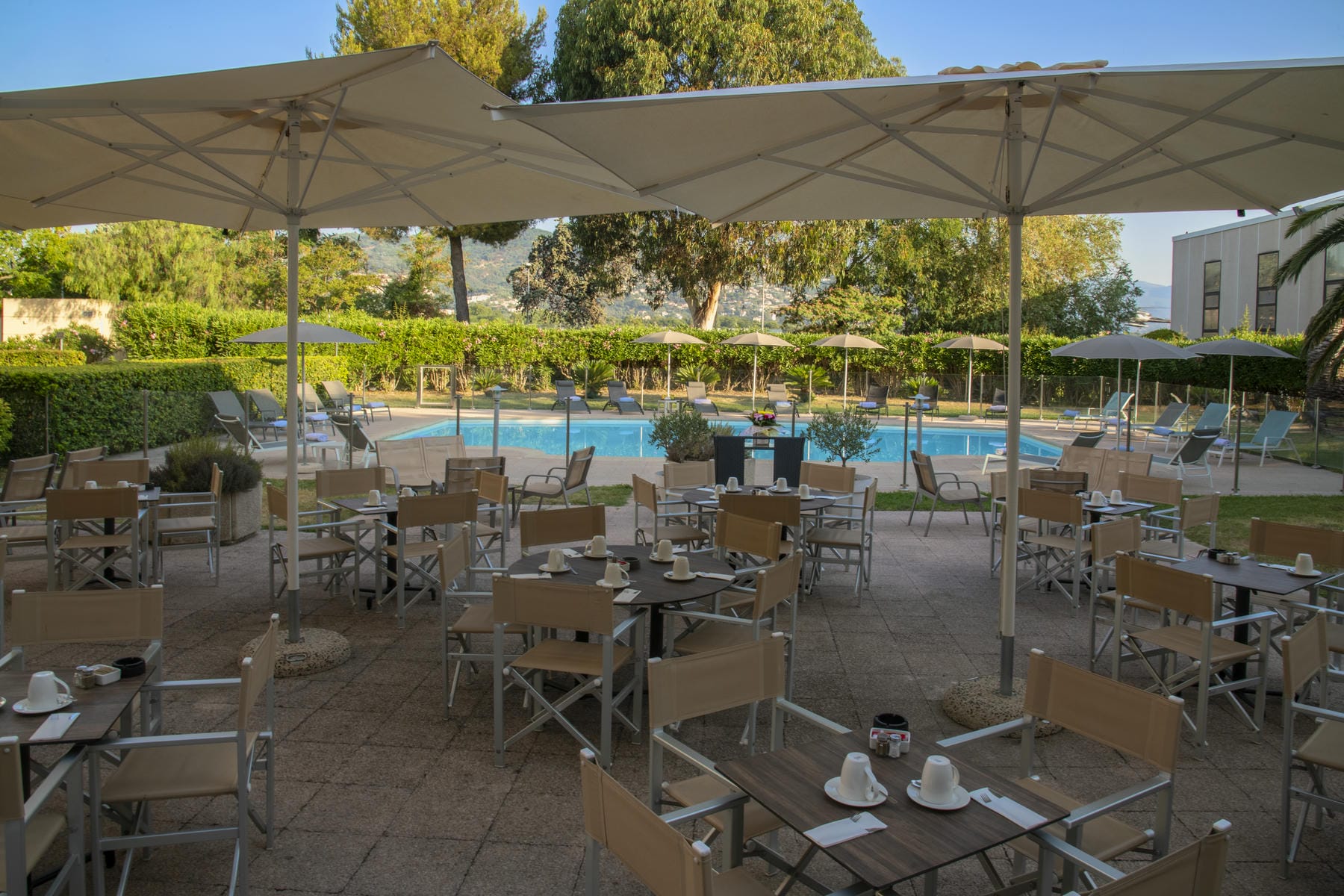 des tables et des chaises sous des parasols devant une piscine