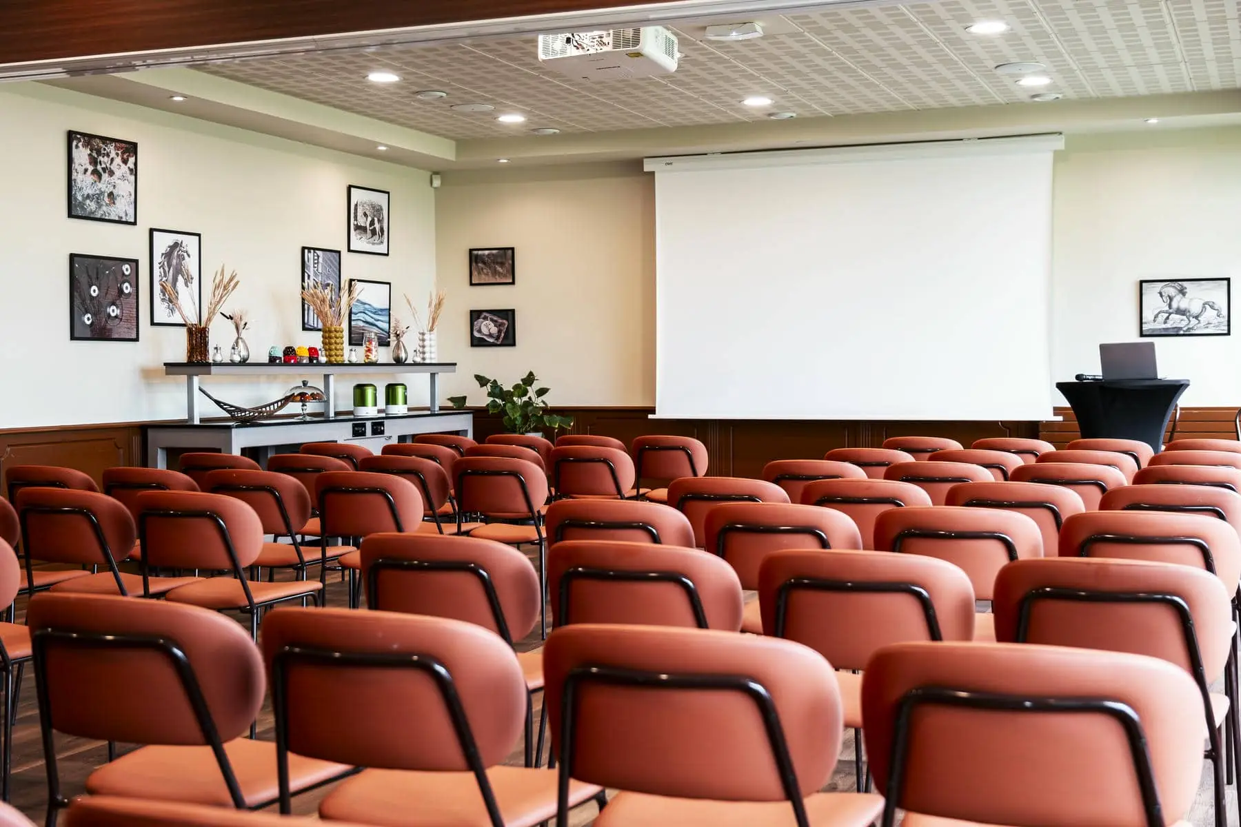 des rangées de chaises rouges devant un écran de projection