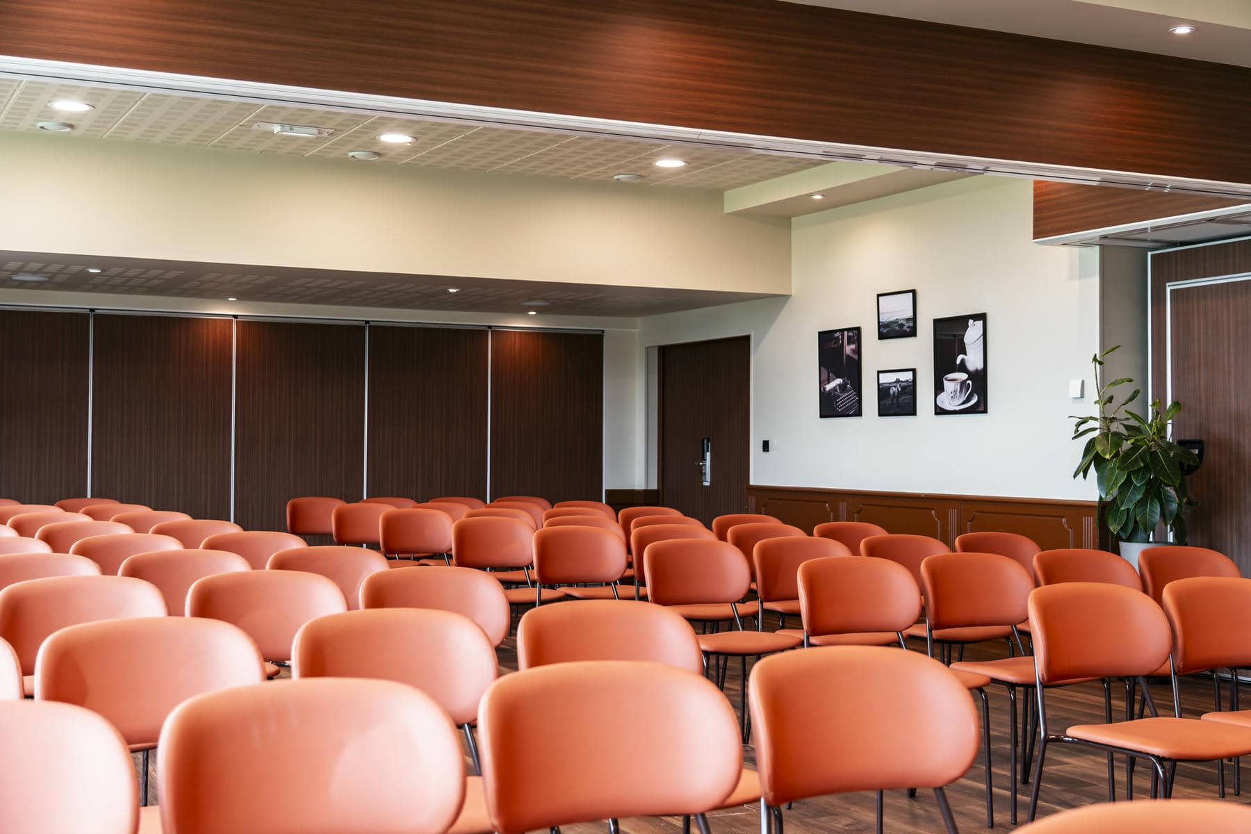 des rangées de chaises orange dans une pièce avec des photos au mur