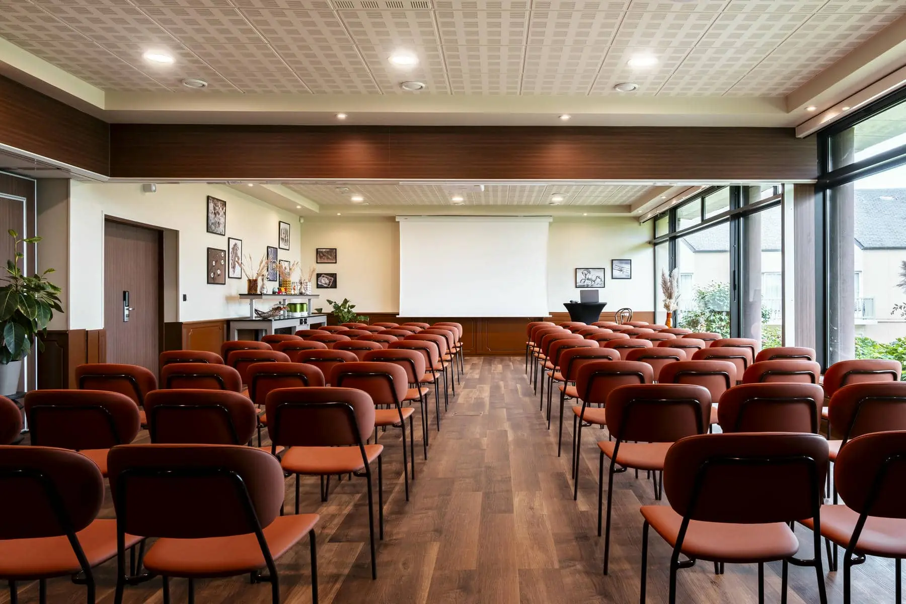 une grande salle avec des rangées de chaises et un écran de projection