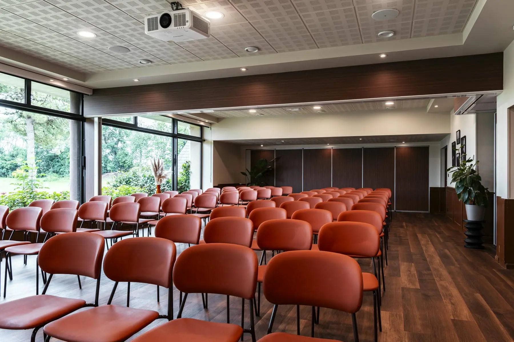 des rangées de chaises orange dans une salle avec un projecteur au plafond