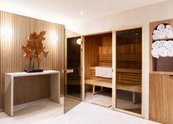 un sauna en bois avec des portes en verre et des serviettes sur des étagères