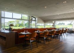 un restaurant avec tables et chaises et vue sur un terrain de golf
