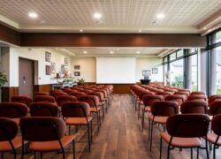 une grande salle avec des rangées de chaises et un écran de projection