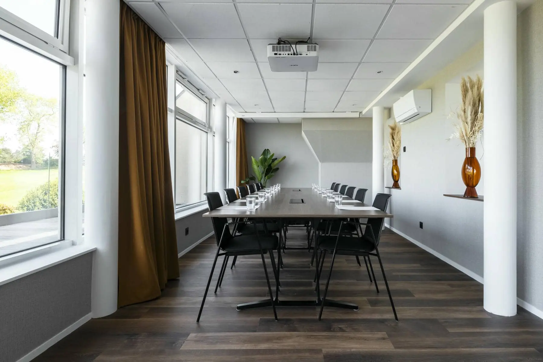 une salle de conférence avec une longue table et des chaises et un projecteur au plafond