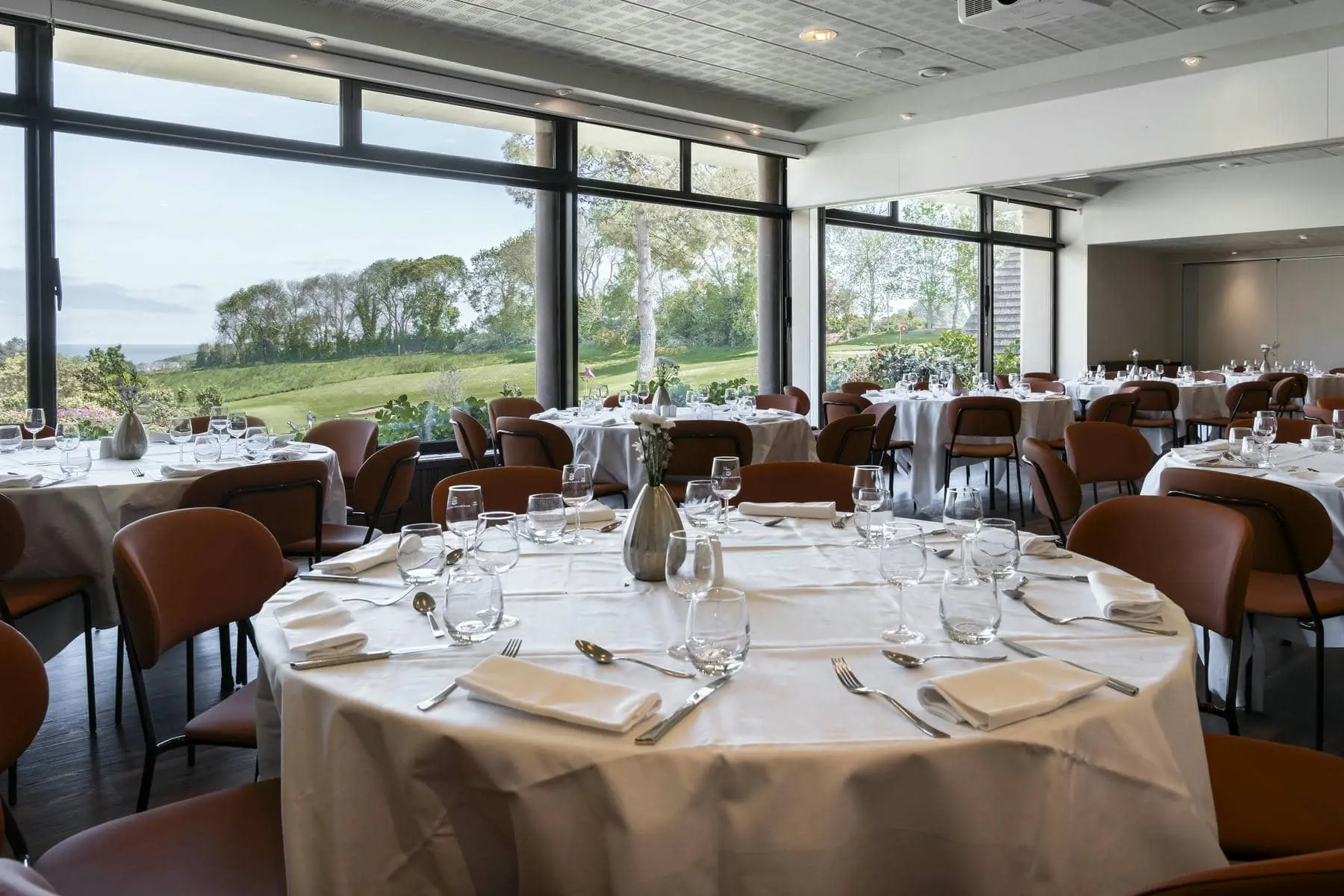 une salle à manger avec tables et chaises et vue sur un terrain de golf