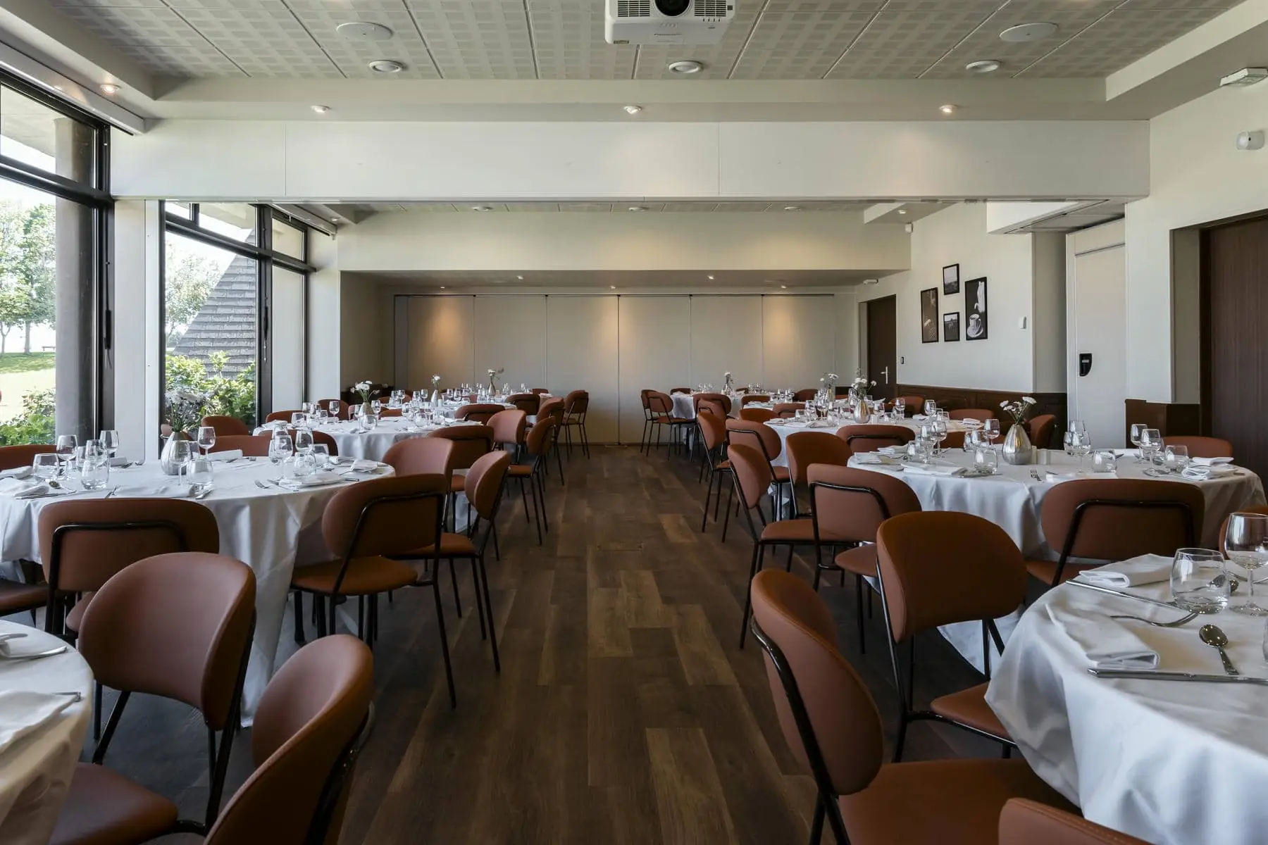 une grande salle avec des tables et des chaises et un projecteur au plafond