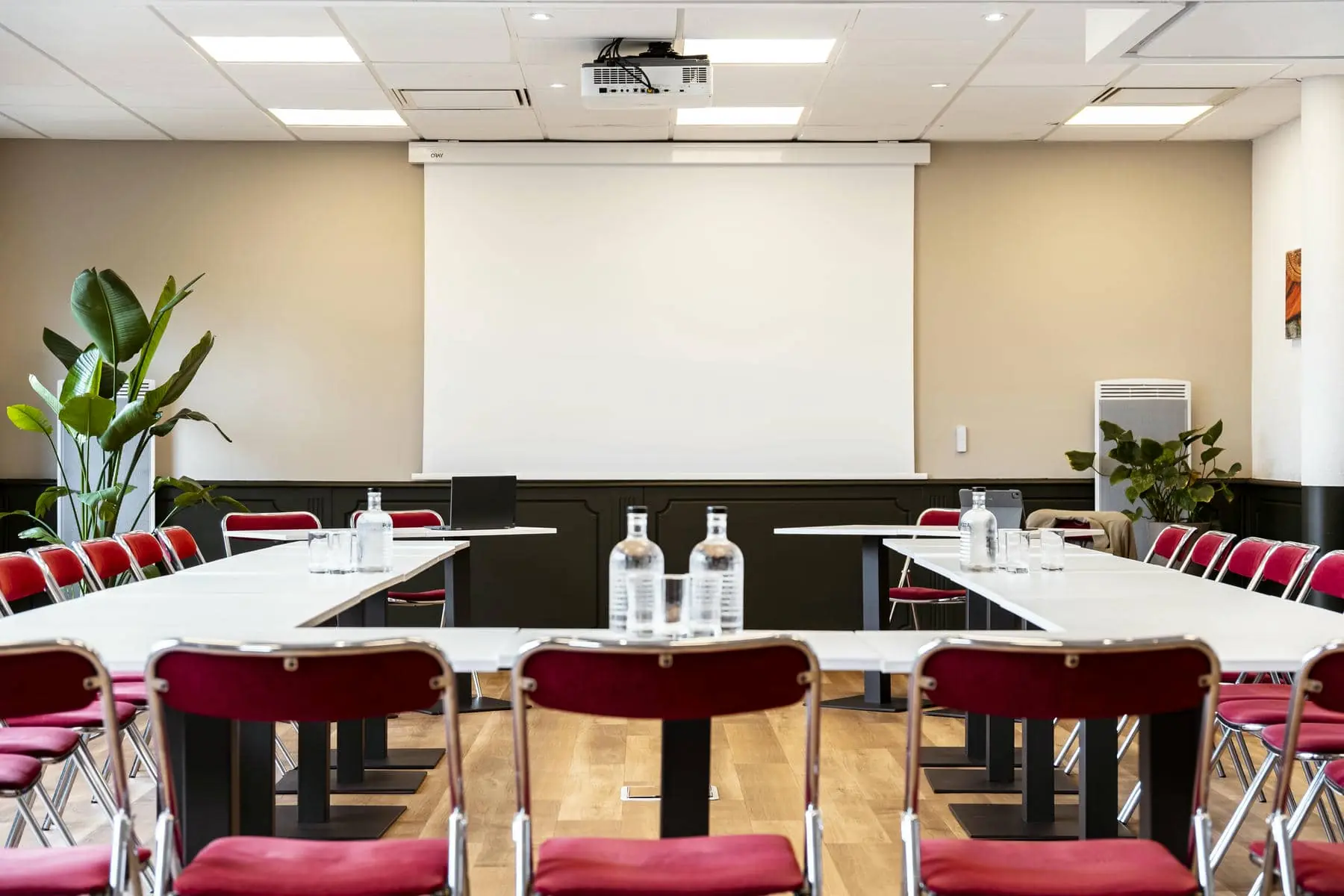 une salle de conférence avec des tables et des chaises et un écran de projection