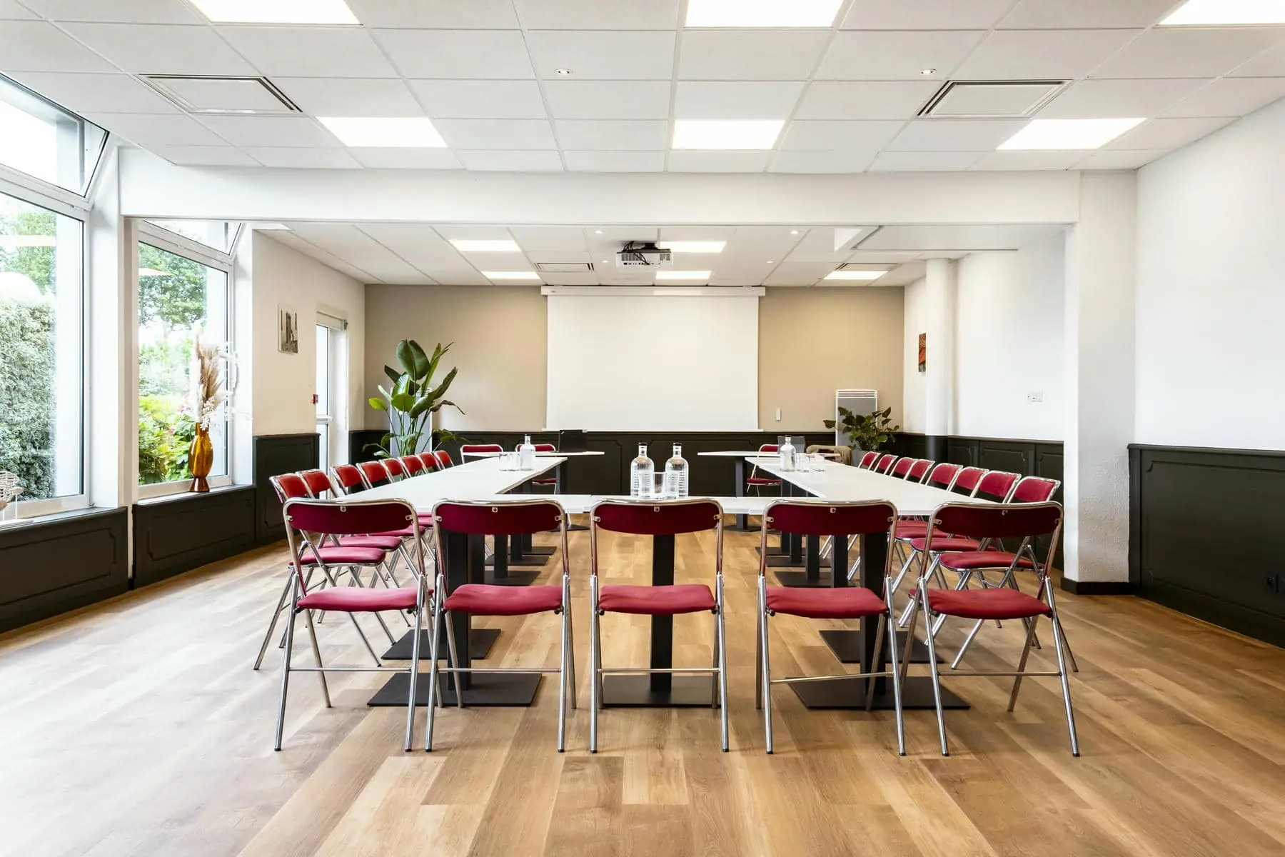 une salle de conférence avec des tables et des chaises et un écran de projection