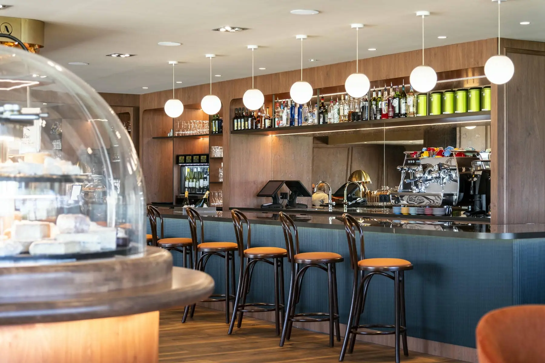 un bar dans un restaurant avec des tabourets et un dôme en verre