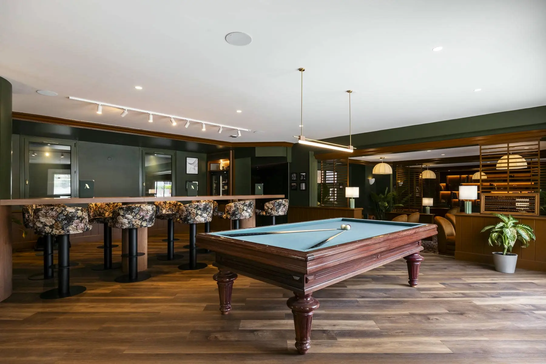 une table de billard dans une salle avec un bar et des chaises