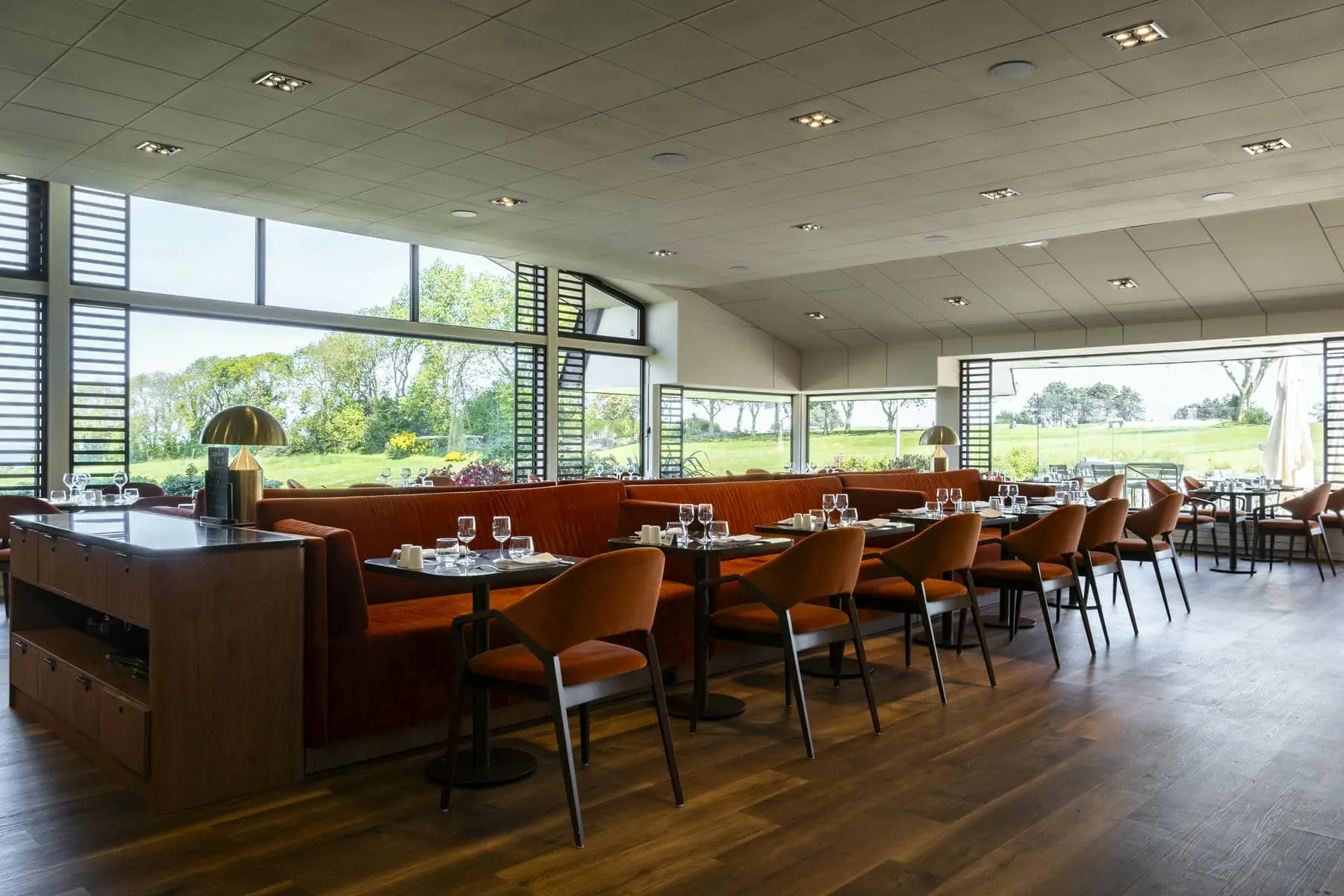 un restaurant avec tables et chaises et vue sur un terrain de golf