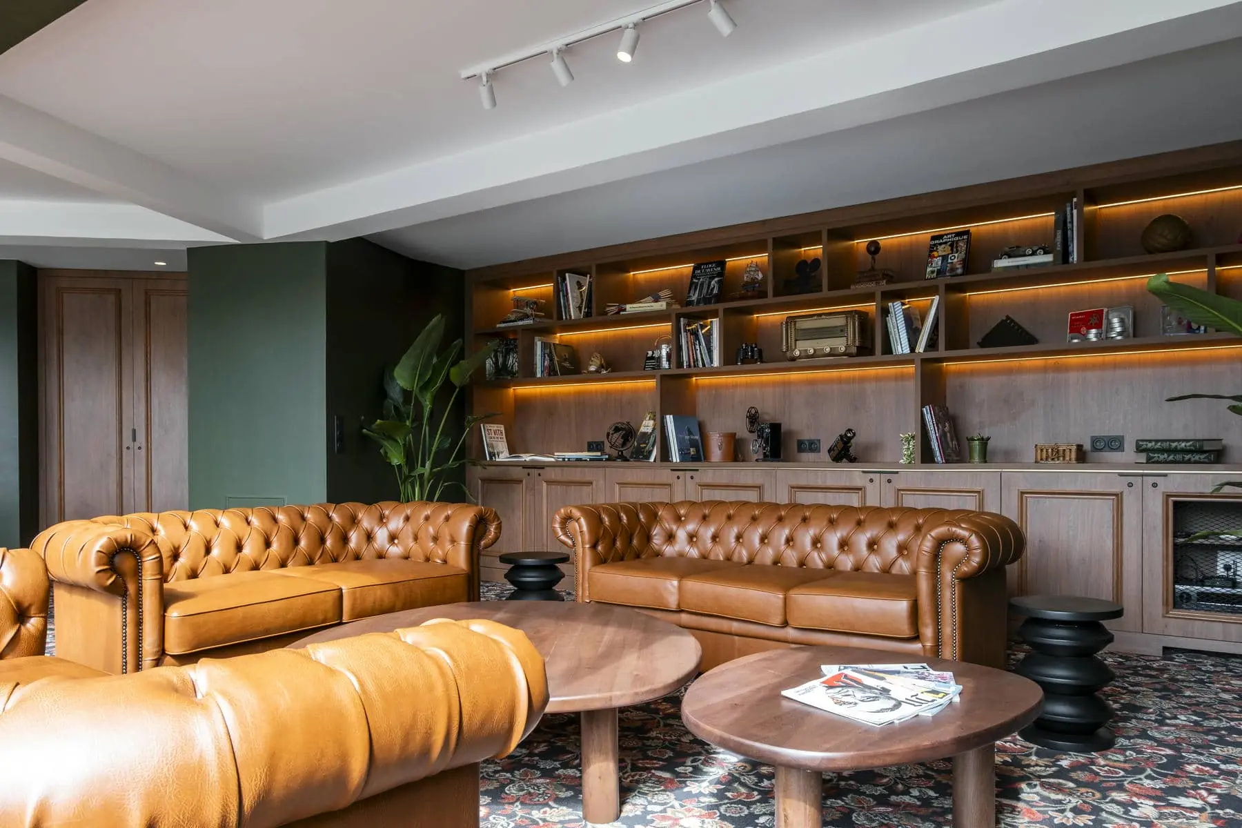 un salon avec un canapé en cuir marron et une bibliothèque