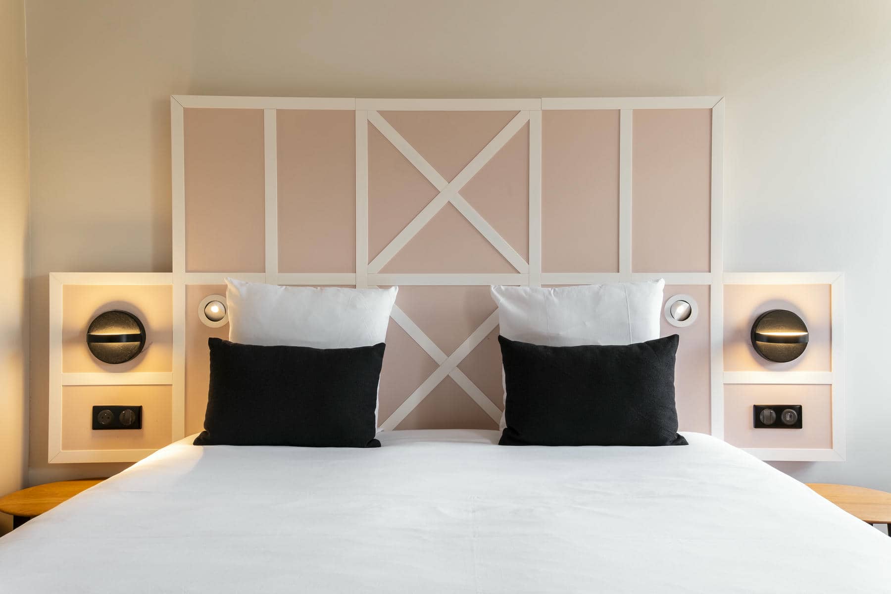 un lit avec une tête de lit rose et blanche et des oreillers noirs