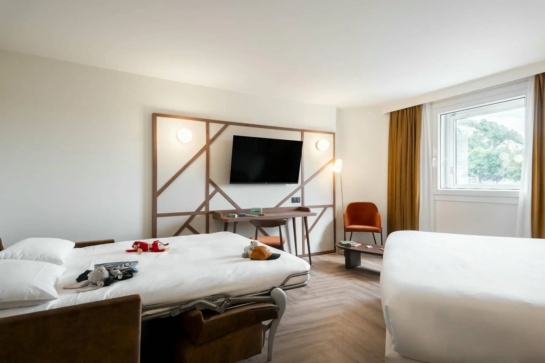 a hotel room with two beds and a flat screen tv