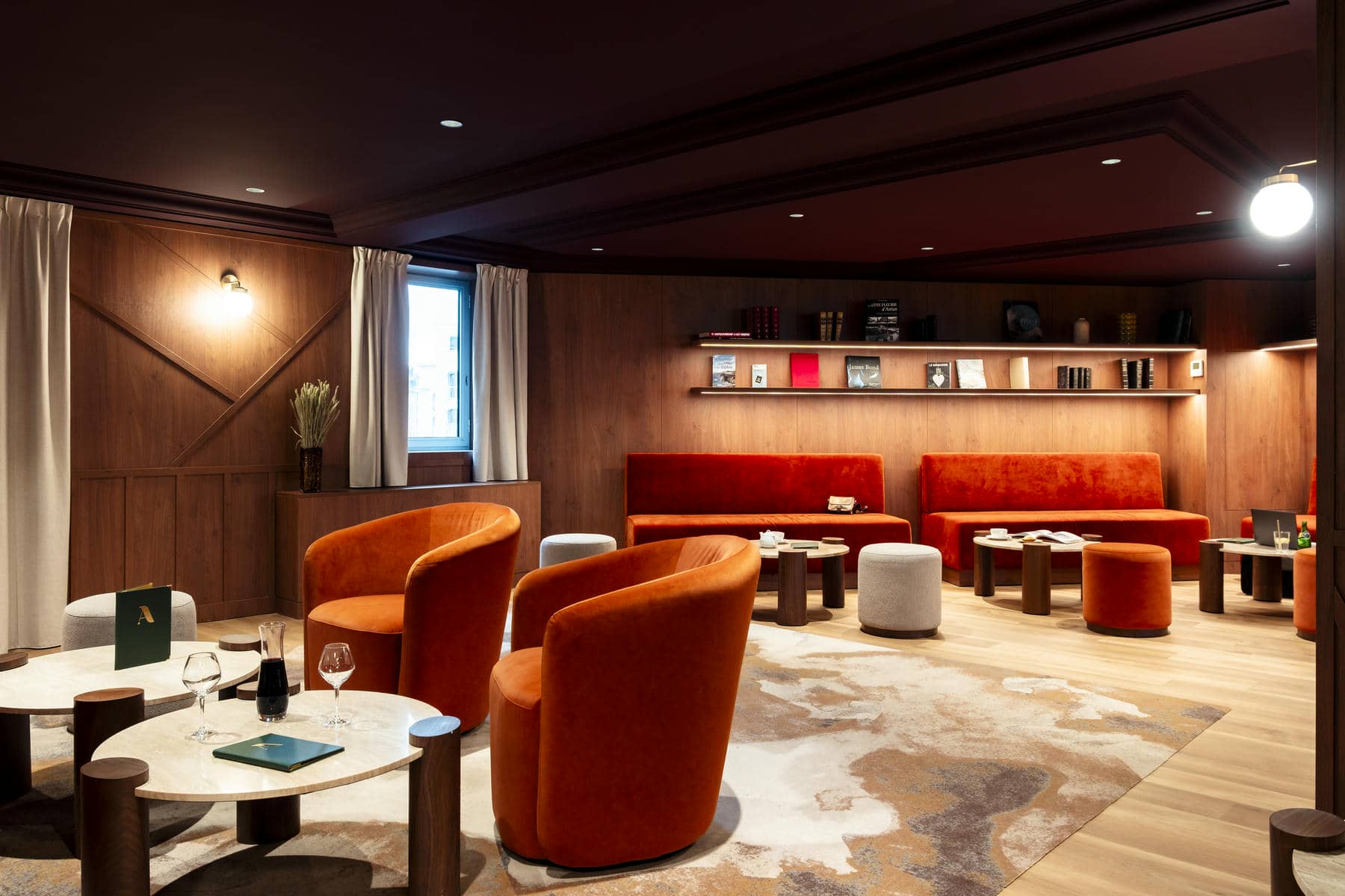 un salon avec des chaises et des tables orange et une étagère avec des livres dessus