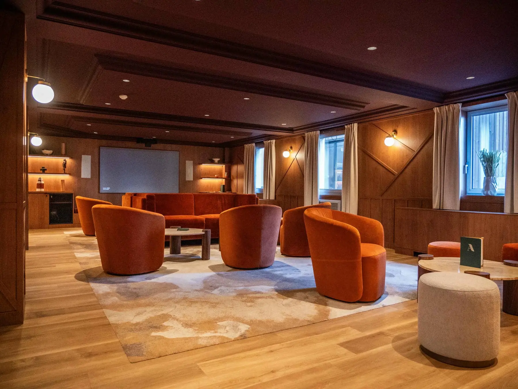 a living room with orange chairs and a projector screen