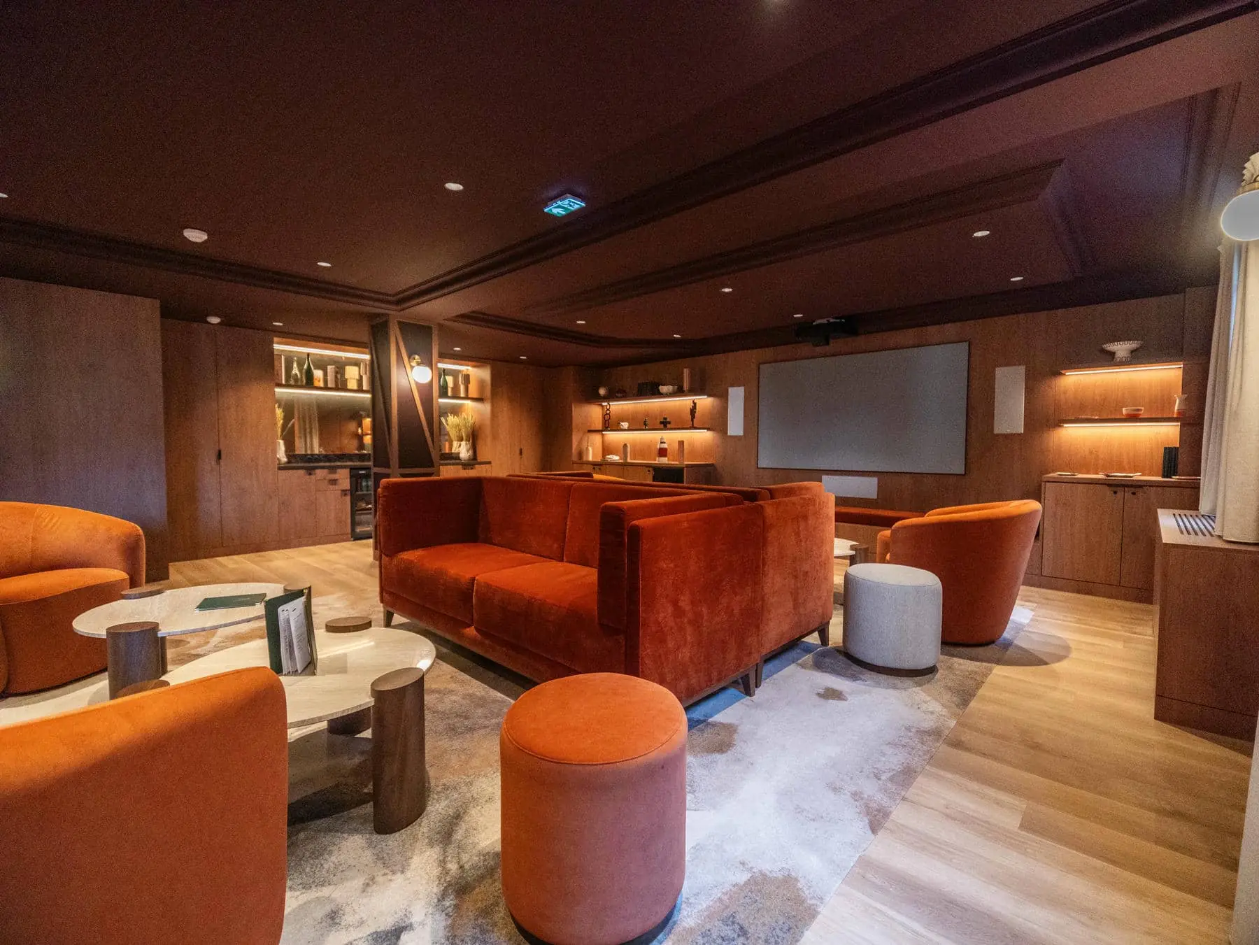 a living room with orange furniture and a projector screen