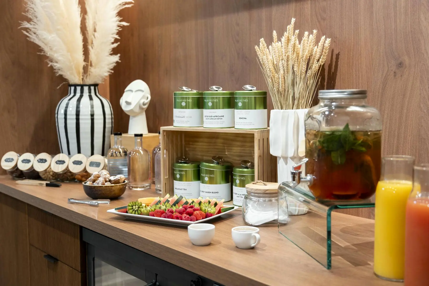 a buffet table with a variety of food and drinks including a jar of herbal tea