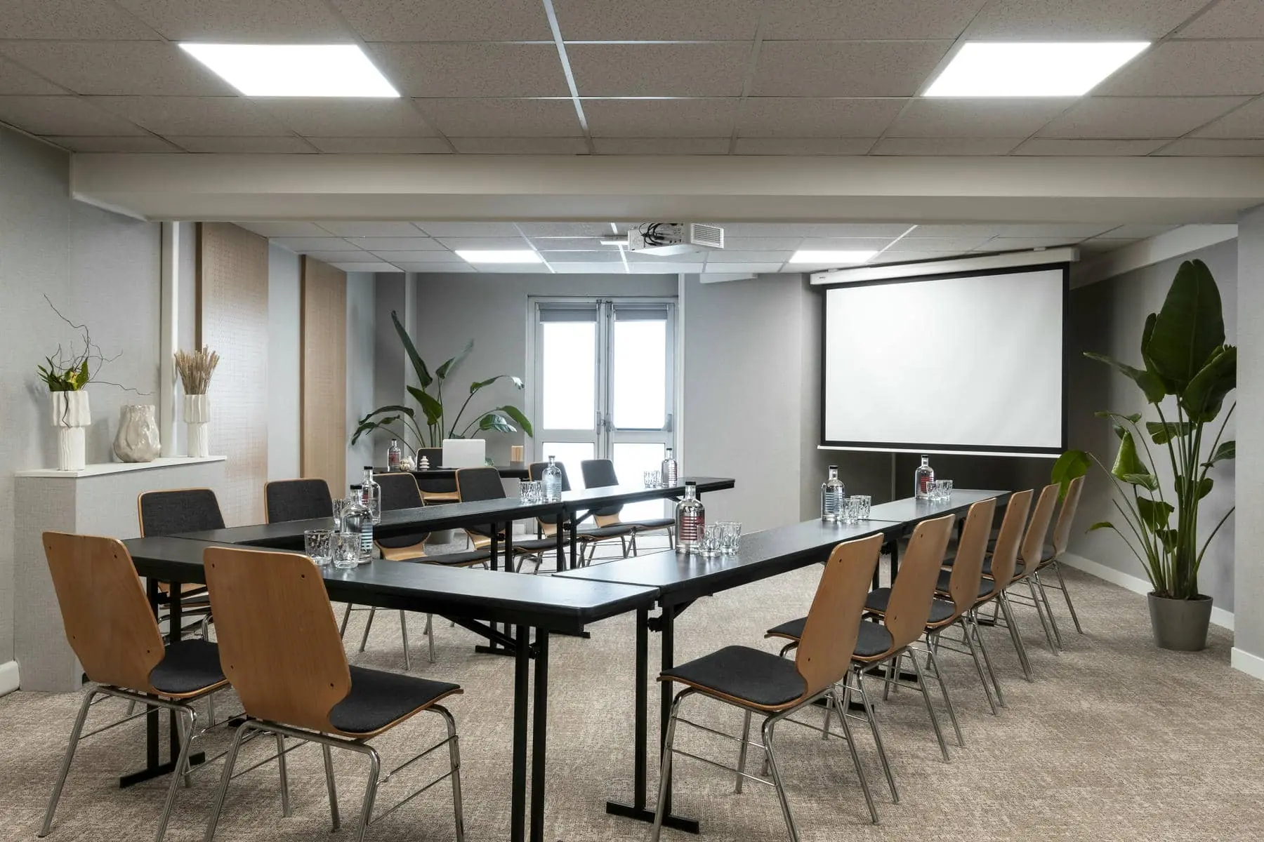 a conference room with tables and chairs and a projector screen