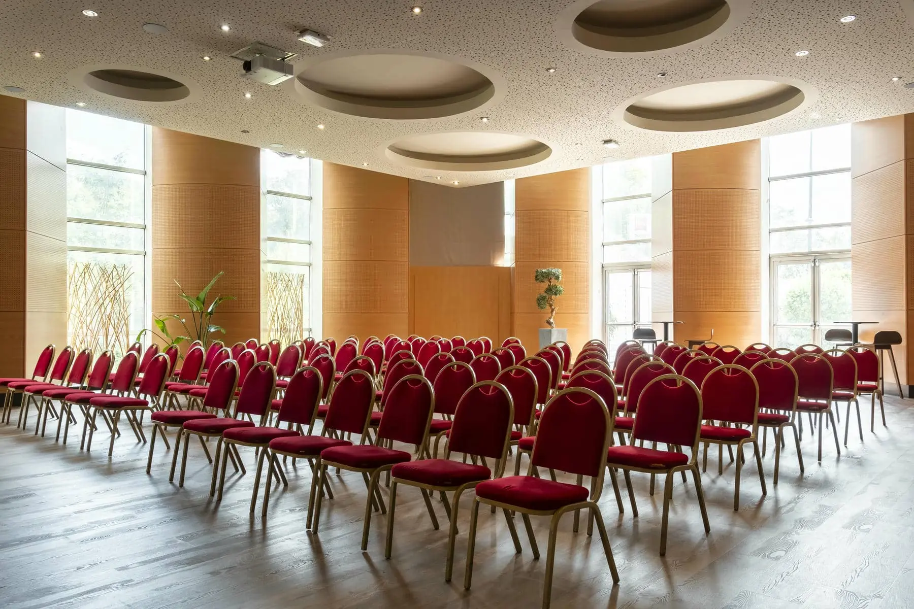 rows of red chairs in a room with a projector on the ceiling