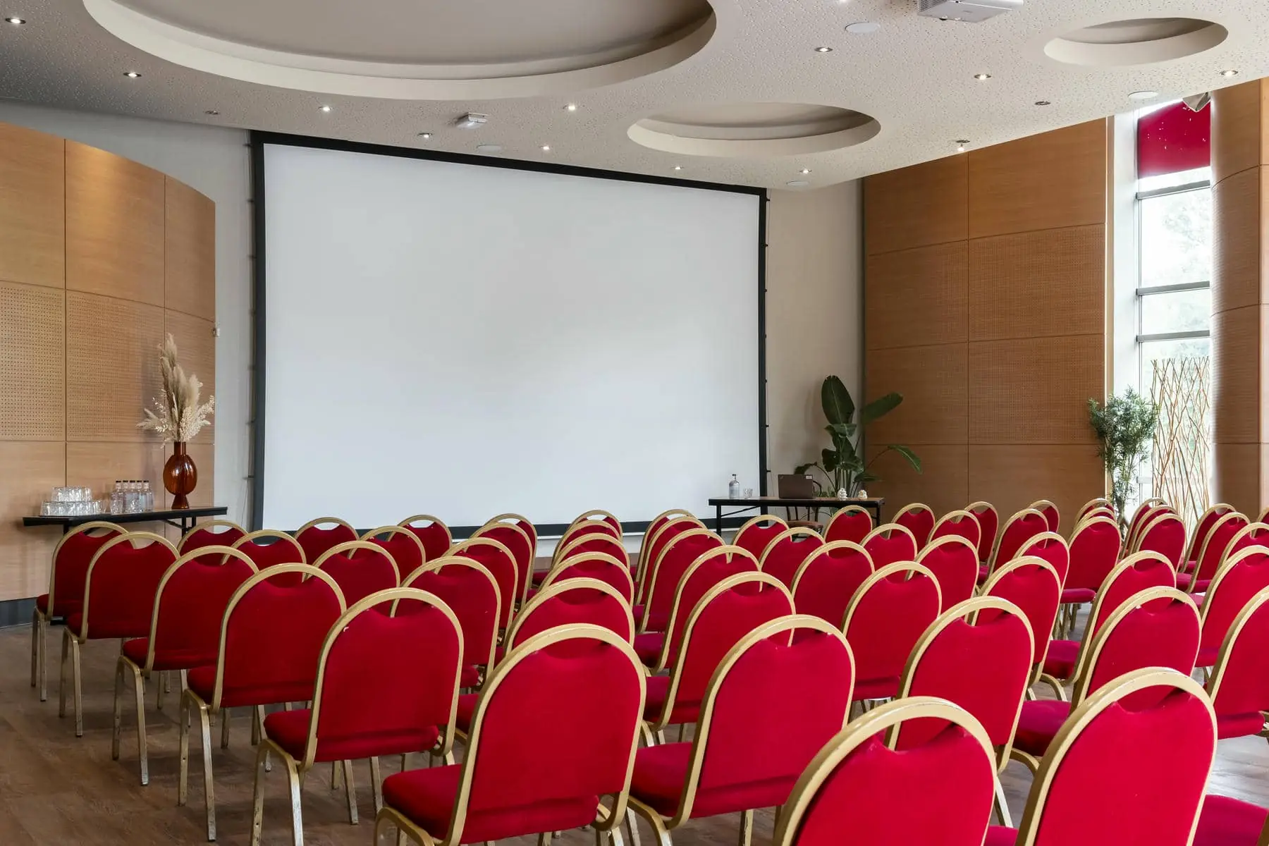 rows of red chairs in front of a projector screen