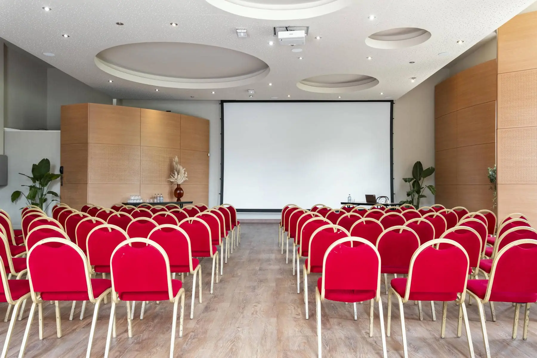 rows of red chairs in front of a projector screen