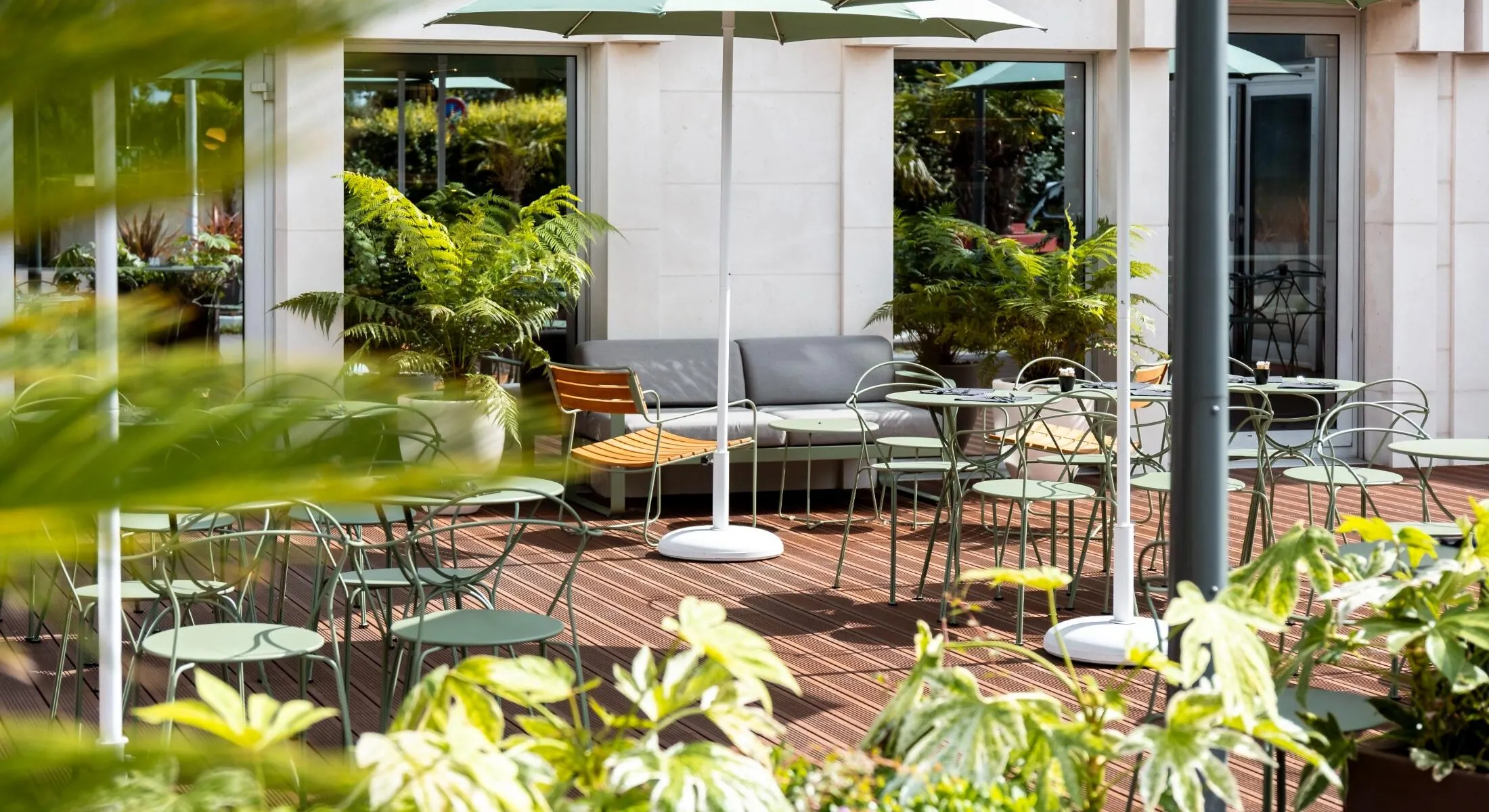 a patio with tables and chairs and green umbrellas
