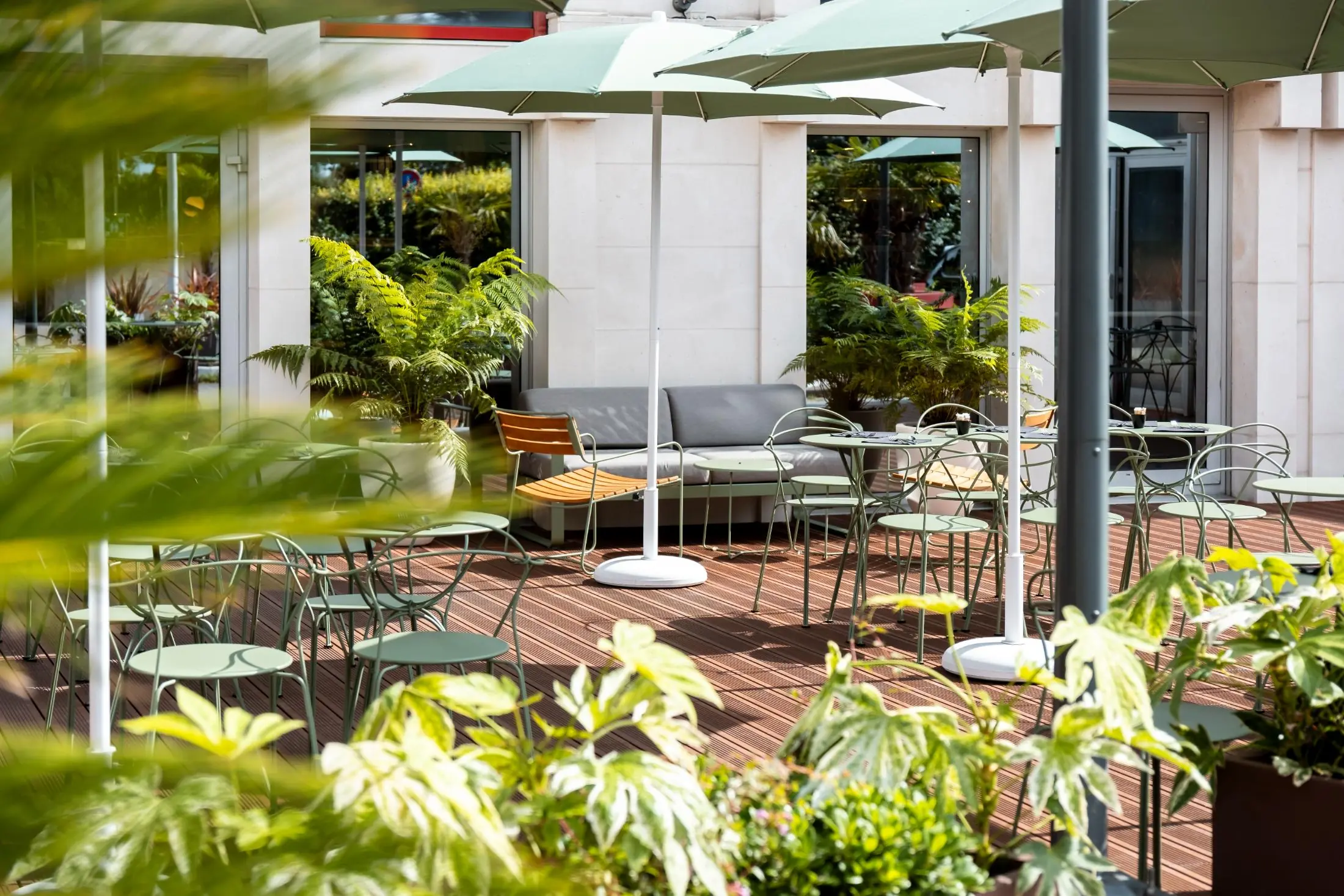 a patio with tables and chairs and green umbrellas