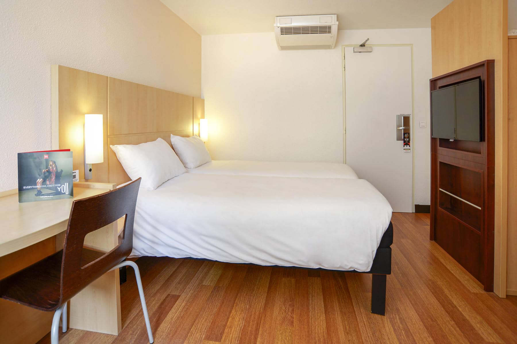 une chambre d'hôtel avec deux lits, un bureau et une télévision