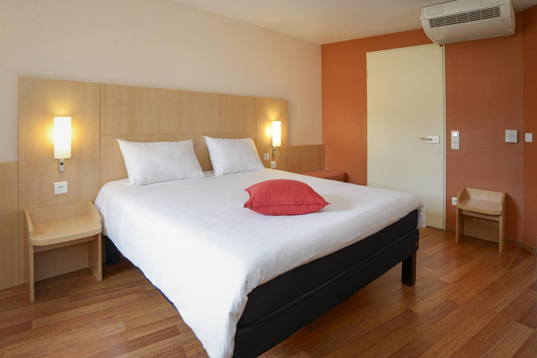 une chambre d'hôtel avec un lit et un oreiller rouge