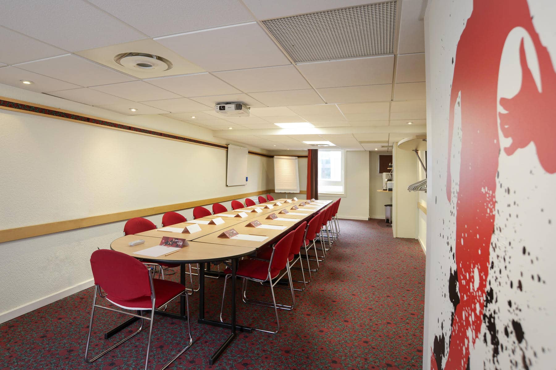 une salle de conférence avec une longue table et des chaises rouges