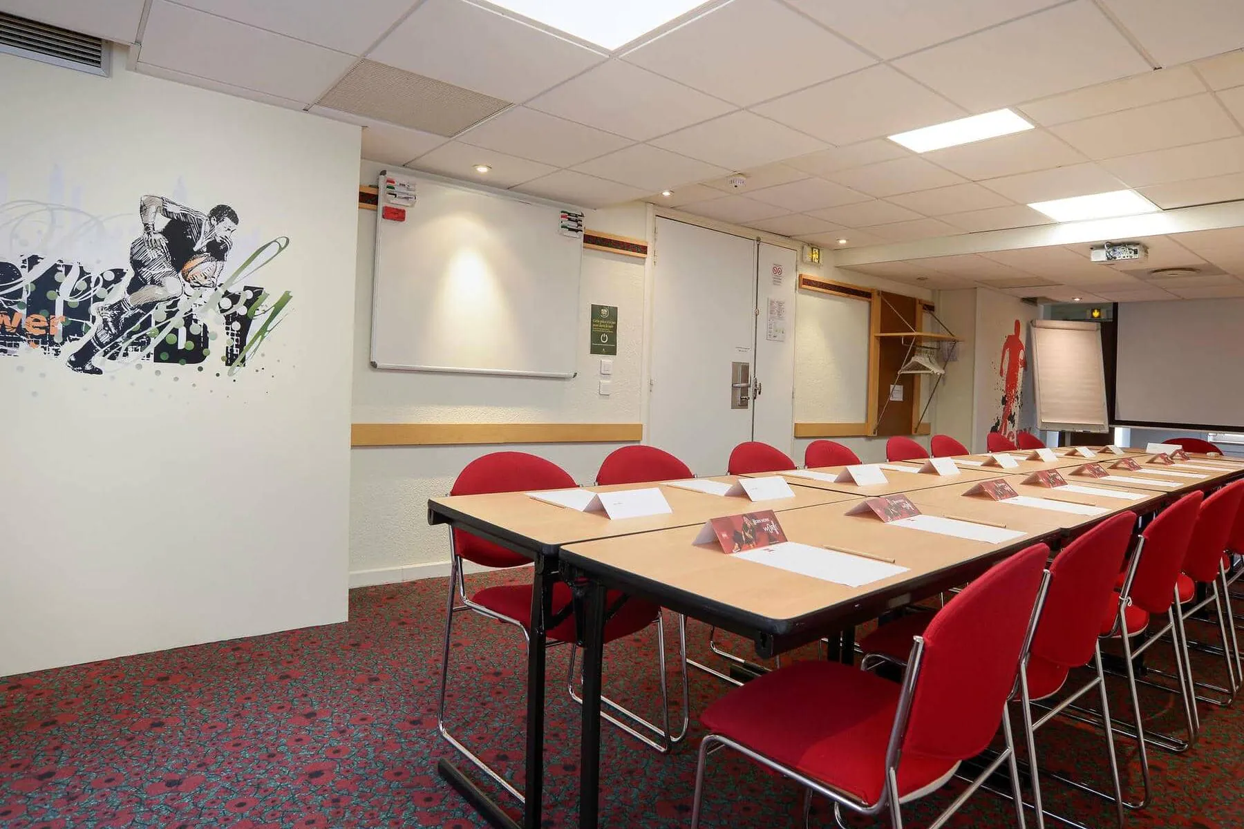 une salle de conférence avec des tables et des chaises et une peinture murale sur le mur qui dit rugby