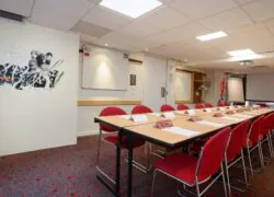une salle de conférence avec des tables et des chaises et une peinture murale sur le mur qui dit rugby