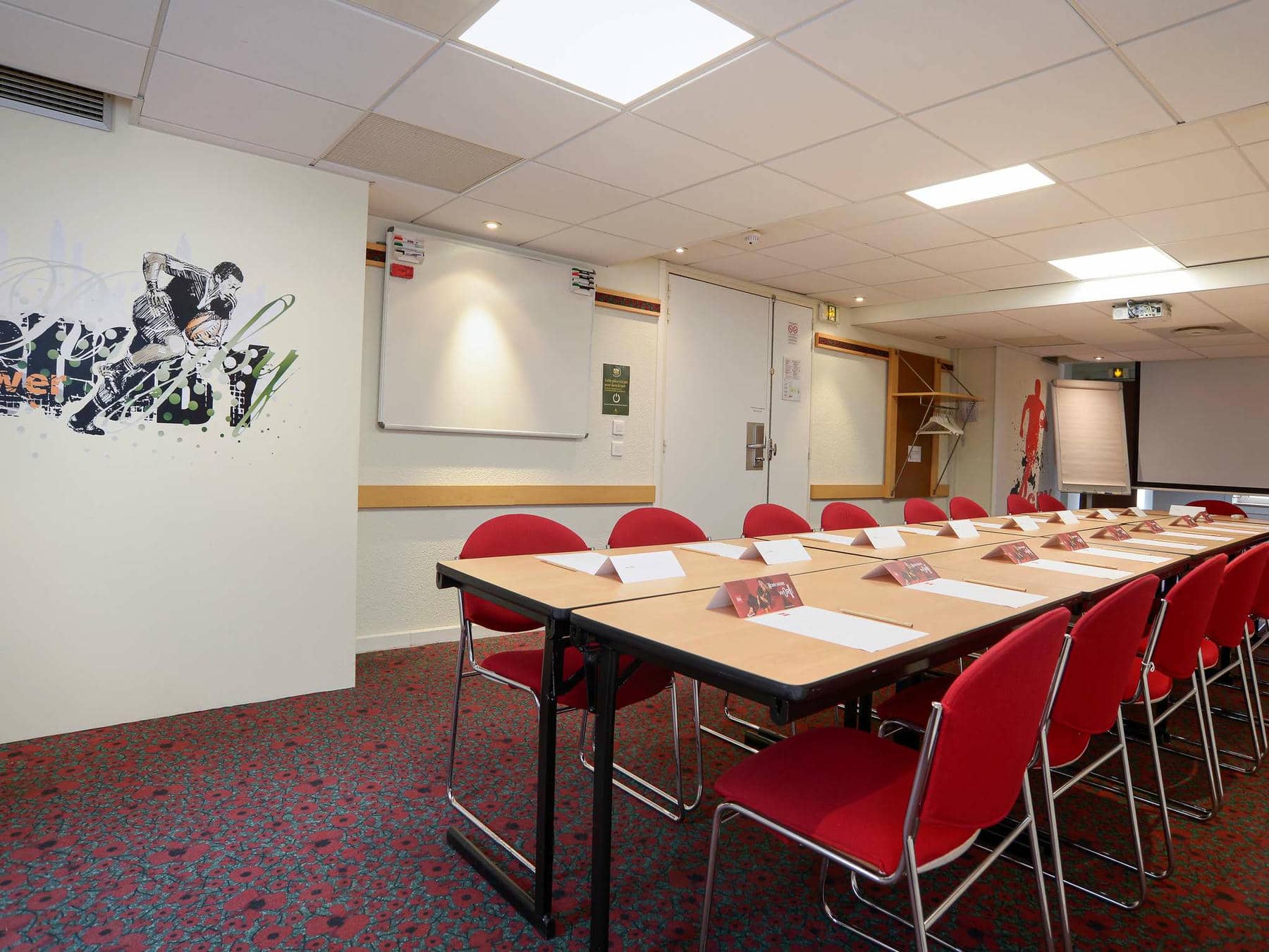une salle de conférence avec des tables et des chaises et une peinture murale sur le mur qui dit rugby