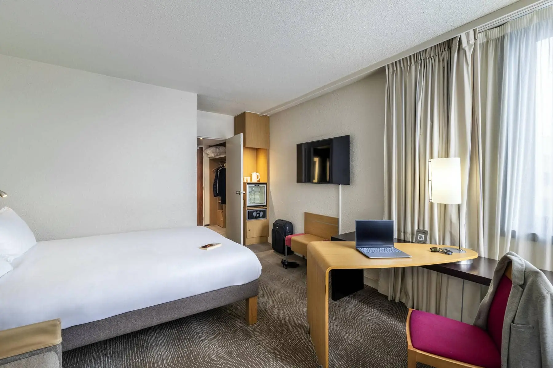 une chambre d'hôtel avec un lit et un bureau sur lequel est posé un ordinateur portable