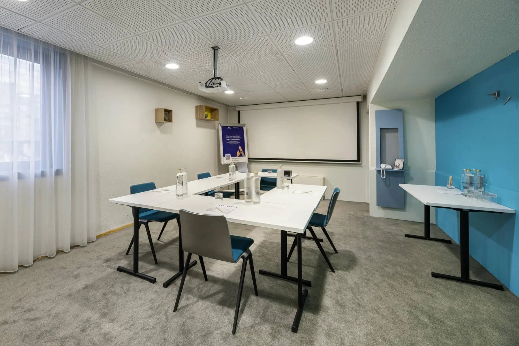 une salle de conférence avec des tables et des chaises et un écran de projection